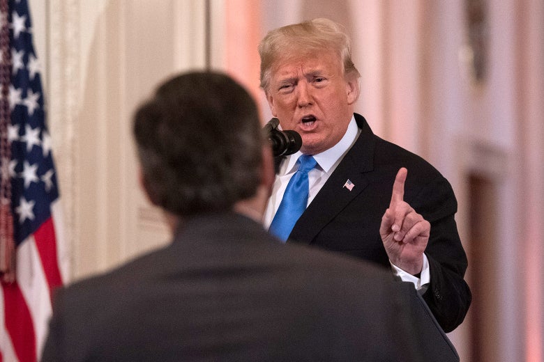 The back of Jim Acosta in the foreground with Donald Trump at a podium behind.